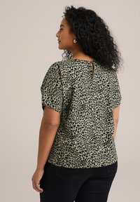 Blusa verde con stampa leopardata, maniche corte, dettaglio a occhiello sul retro e vestibilità rilassata, realizzata in tessuto leggero.