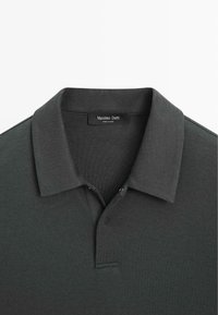 Grijs poloshirt gemaakt van zachte stof, met een klassieke kraag, knoopsluiting met twee knopen en subtiele gestikte details.