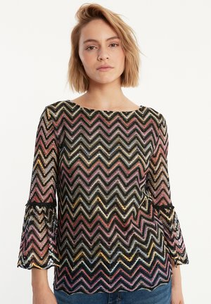 Zwarte shirt met zigzagpatroon in roze, goud en blauwe tinten. Heeft lange klokmouwen en een ronde halslijn, gemaakt van lichte stof.