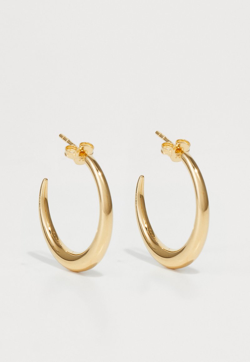 Orecchini a cerchio in metallo dorato con design curvato e allungato e superficie liscia; dotati di una chiusura posteriore sicura.