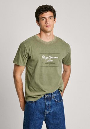 Groen katoen t-shirt met korte mouwen, voorzien van een gedrukt logo vak in het midden aan de voorkant, gecombineerd met blauwe denim jeans.