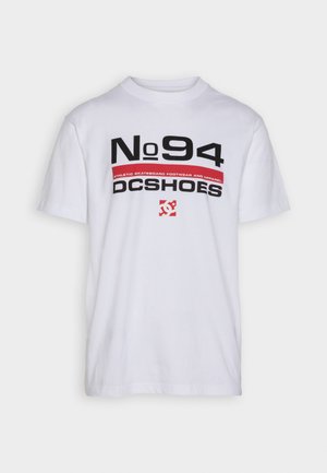 Biała bawełniana koszulka z wyrazistym czarnym i czerwonym napisem: "No 94" oraz "DC SHOES" z logo. Klasyczny fason z okrągłym dekoltem i krótkimi rękawami.
