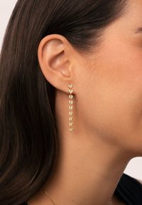 Gold-tone earrings featuring multiple heart-shaped accents arranged in a vertical line, showcasing a shiny finish and delicate design.