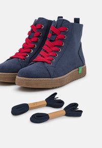 Navy suede high-top shoes with red laces, brown rubber sole, green logo detail. Two additional navy laces included.