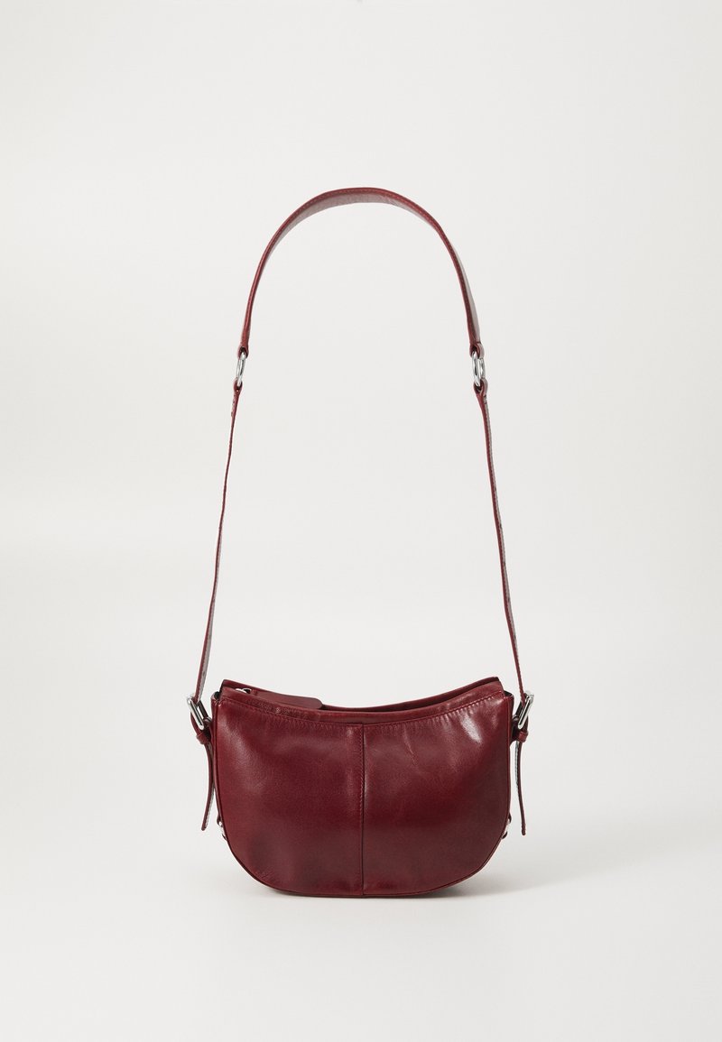Borsa a spalla in pelle rossa con forma curvilinea, texture liscia e una strap regolabile sottile. Presenta accessori in tono argento e un design semplice.