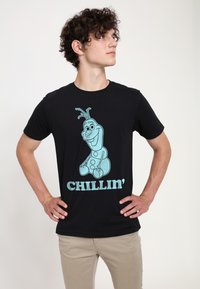 Sort bomulds t-shirt med en lyseblå grafik af en tegneseriefigur og ordet "CHILLIN'" i matchende farve, rund halsdesign.