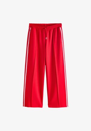 Pantalons de sport rouges à jambes larges, dotés d'une taille élastique et de bandes blanches sur les côtés. Fabriqués dans un matériau lisse et léger.