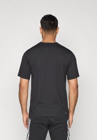 Juodas trumpomis rankovėmis marškinėliai, pagaminti iš minkštos medžiagos, su klasikinio apvalaus kaklo iškirpte; turi laisvą siluetą ir paprastą dizainą be raštų ar akcentų.