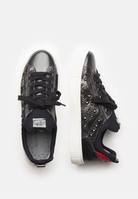 Mustat lenkkarit metallisilhuetteilla, niitityksellä, sileällä nahkakärjellä, teksturoiduilla sivuilla ja valkoisilla kumipohjilla. Varustettu mustilla nauhoilla.