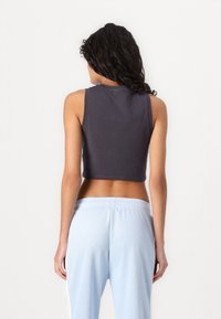 Top scurt fără mâneci din bumbac gri închis, cu un croi lejer și decolteu rotund. Asortat cu pantaloni jogger bleu deschis, cu talie elastică.