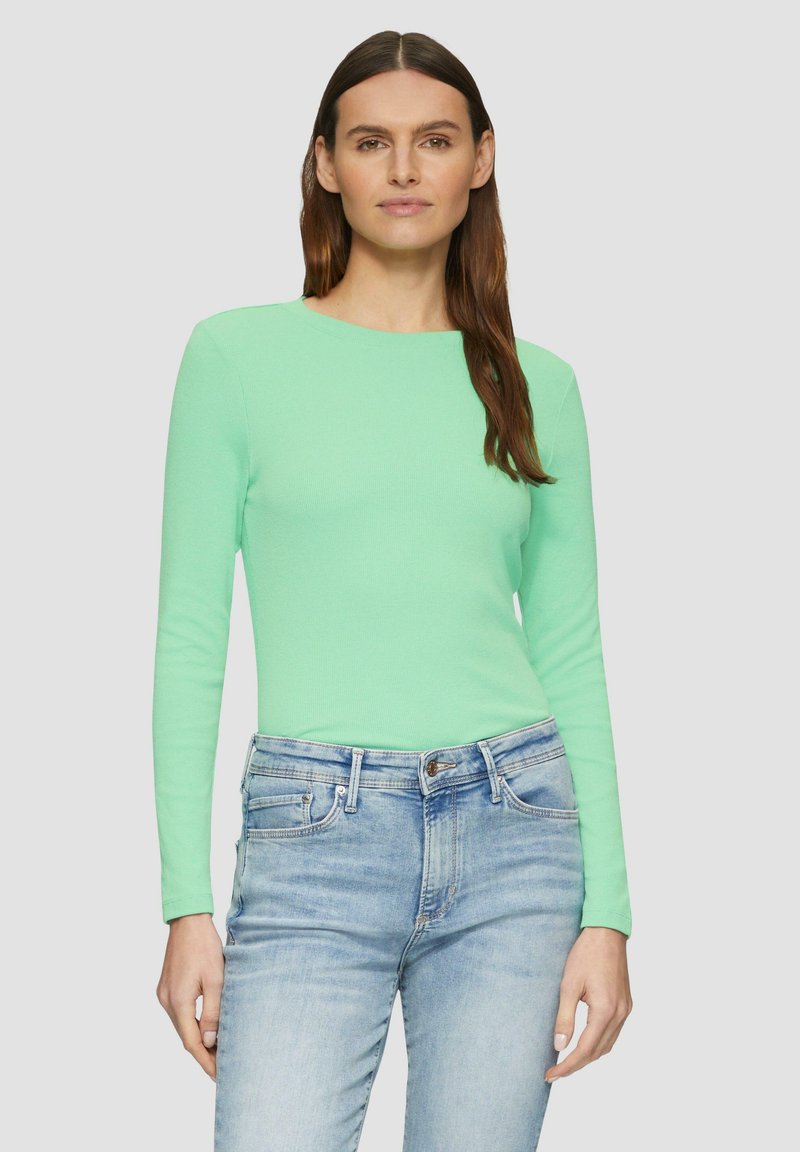 Haut à manches longues vert menthe avec une texture côtelée, décolleté rond et coupe ajustée, associé à un jean en denim bleu clair.