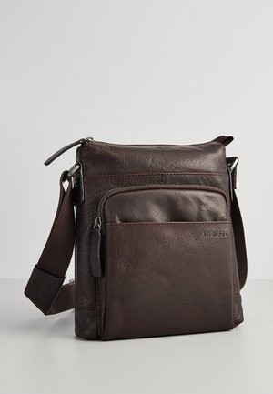 Dunkelbraune Leder-Umhängetasche mit vorderer Reißverschlusstasche und verstellbarem braunem Stoffriemen, auf einer grauen Oberfläche platziert.