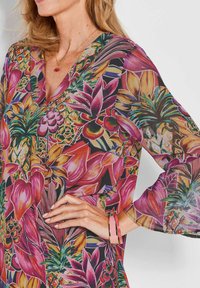 Blumen-Wickelbluse mit lebhaften Pink-, Lila- und Grüntönen. Hergestellt aus leichtem, durchscheinendem Material mit Glockenärmel und V-Ausschnitt.