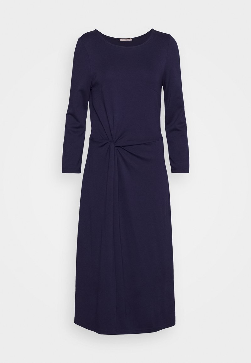 Granatowa sukienka z długimi rękawami i okrągłym dekoltem, z akcentem w postaci skręconego węzła w talii oraz gładką, miękką teksturą.