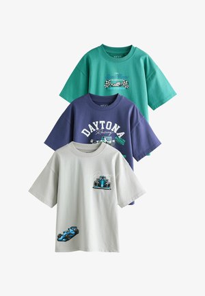 Három rövid ujjú, verseny témájú póló özönkék színben: türkiz, tengerészkék és bézs, mindegyiken versenyautó grafikák és szöveg található az elején.