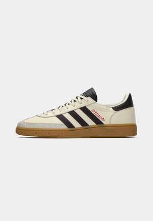 Cream and black Adidas Spezial sneaker with gum sole, black stripes, red stitching, and "Spezial" branding on side.