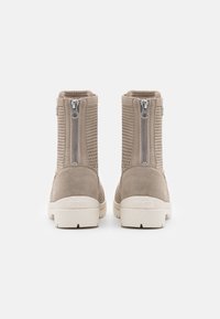 Botas de tobillo marrones con una parte superior texturizada, cremalleras laterales y una suela acolchada. Materiales lisos y perforados mejoran la transpirabilidad.