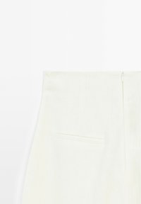 Linenowe spodnie w jasnym kremowym kolorze, z ukrytym zamek błyskawicznym i jedną tylną kieszenią o płaskim designie.