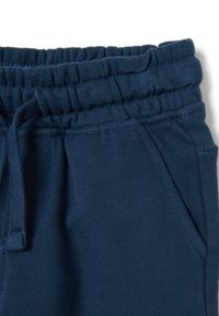 Pantalones de chándal azul marino con cintura elástica y cordón. Cuenta con bolsillos laterales y tejido de algodón suave y texturizado.