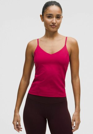 Tætsiddende, ærmeløs top i vibrerende fuchsia, med V-halsudskæring, tynde stropper, glat tekstur og diskret sømdetaljering.