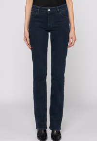 Tmavě modré rovné džíny vyrobené z denimu. Mají pět kapes, poutka na opasek a zapínání na předním knoflíku. Hladká textura a klasický design.