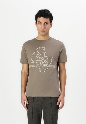 Brown cotton t-shirt with a round neckline, featuring a white logo print of "GUESS?, INC. CLASSIC DESIGN" at the center.
