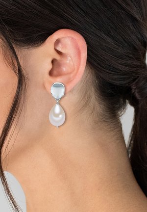 Los pendientes de gota de plata cuentan con una parte superior redonda texturizada y un colgante de perla blanca ovalada y suave, añadiendo elegancia y contraste.