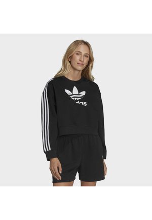Felpa corta nera con logo Adidas bianco, con tre strisce bianche sulle maniche e una vestibilità comoda. Indossata con pantaloni corti coordinati.