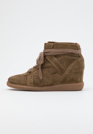 Brązowe zamszowe sneakersy na koturnie z perforowanymi panelami, sznurowaniem z przodu i wyściełanym kołnierzem wokół kostki, na płaskiej powierzchni na białym tle.