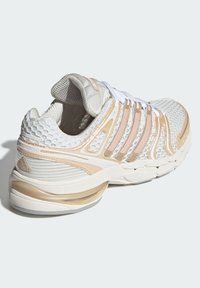 Balta sporta apavi ar bēšiem akcentiem, acu auduma augšdaļu un teksturētām detaļām. Aprīkoti ar šņorēm, mīkstinātu zolīti un strukturētu dizainu.