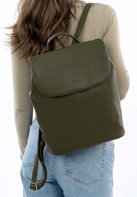 Sac à dos en cuir vert olive avec une finition texturée, un rabat à fermeture et des bretelles ajustables. Design simple et minimaliste sans marque visible.