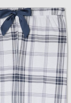 Pantaloni del pigiama bianchi con un motivo a quadretti grigi e neri e un fiocco in tessuto blu navy legato all'elastico in vita.