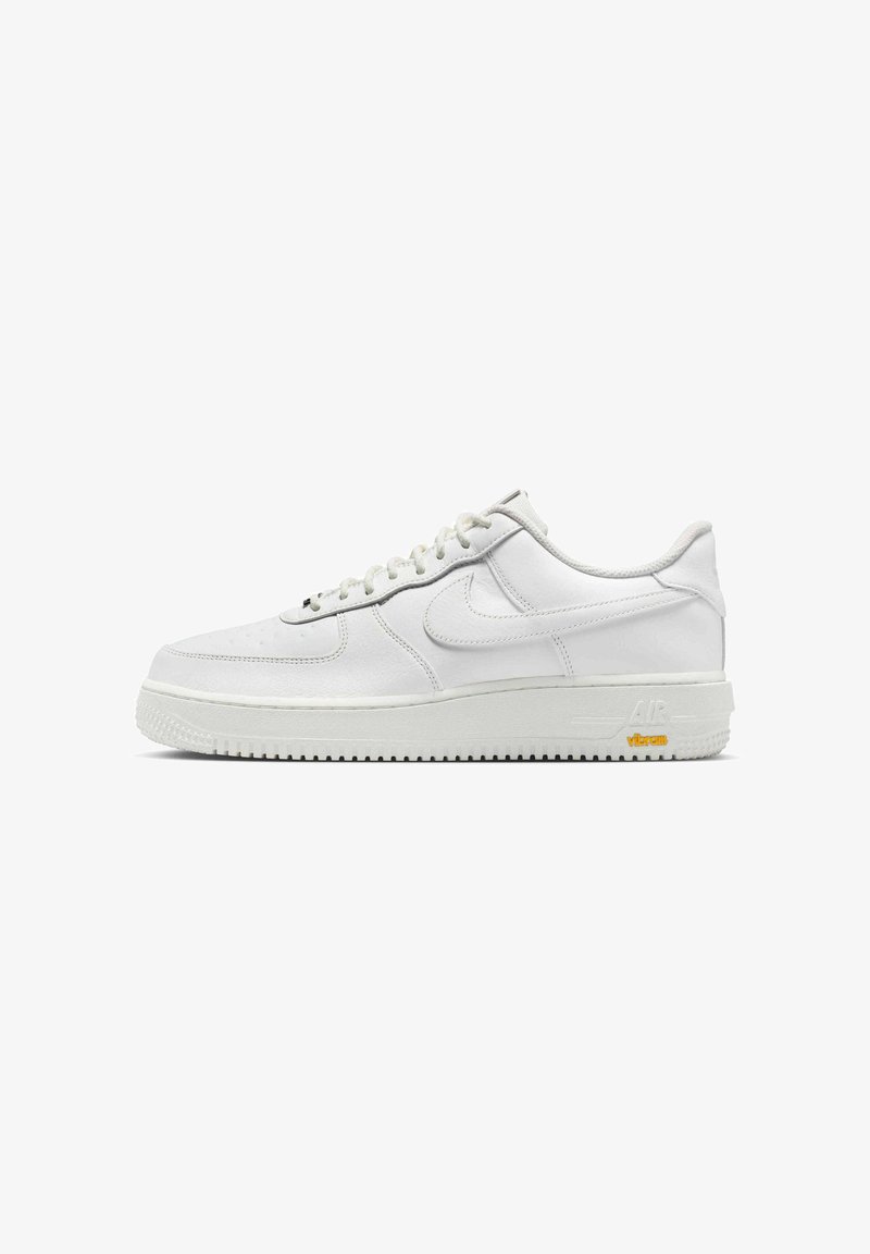 White leather sneaker with round toe, lace-up closure, textured midsole, and contrasting rubber outsole. Features "Air" and "Vibram" branding.