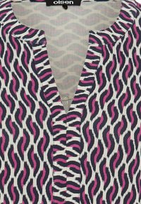 Gemusterte Bluse mit schwarzen, weißen und pinken wellenförmigen Streifen. V-Ausschnitt, kurze Ärmel, leichtes Material mit glatter Textur.