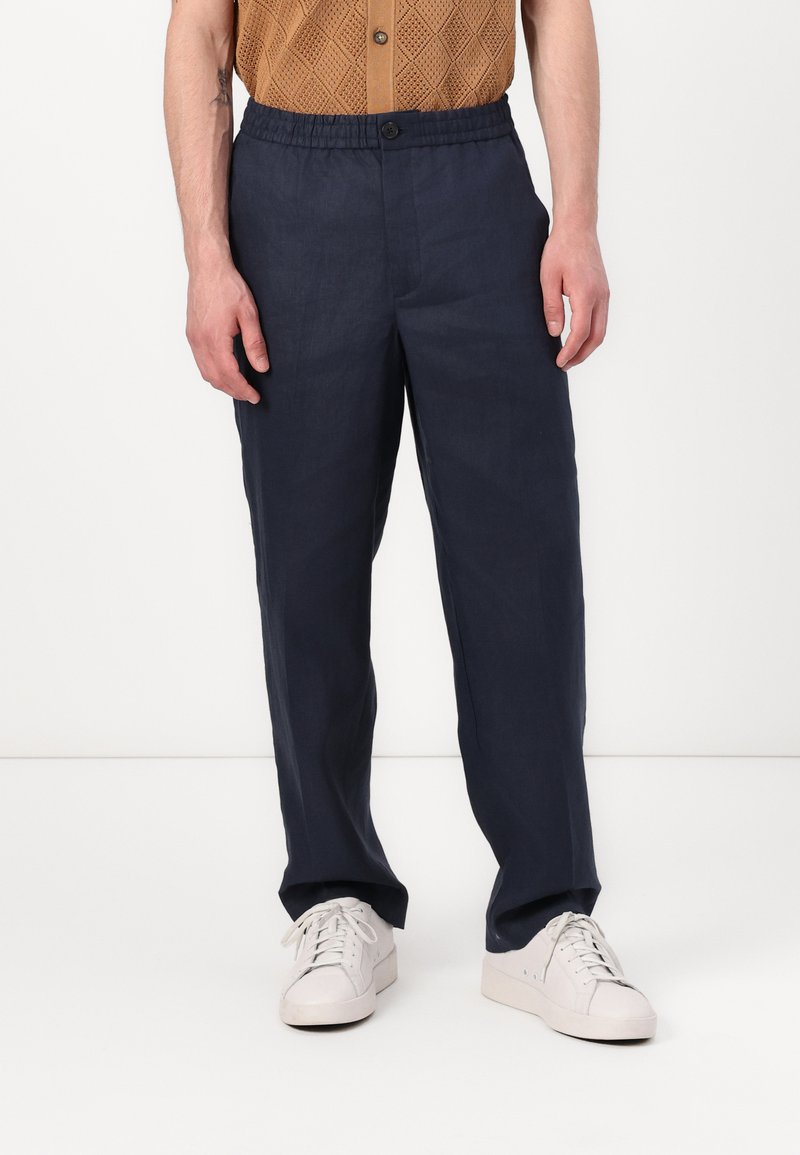 Navy blue, lightweight linen pants with an elastic waistband and button closure. Straight leg design, paired with white sneakers.