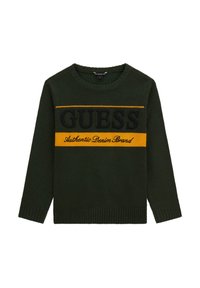 Maglione verde a maglia con maniche lunghe, scollatura rotonda, caratterizzato da un motivo a righe nero e giallo con il testo "GUESS" e "Authentic Denim Brand".