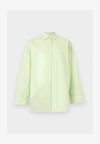 Chemise vert clair à manches longues avec boutons, col et poche poitrine, présentée sur un fond clair uni.