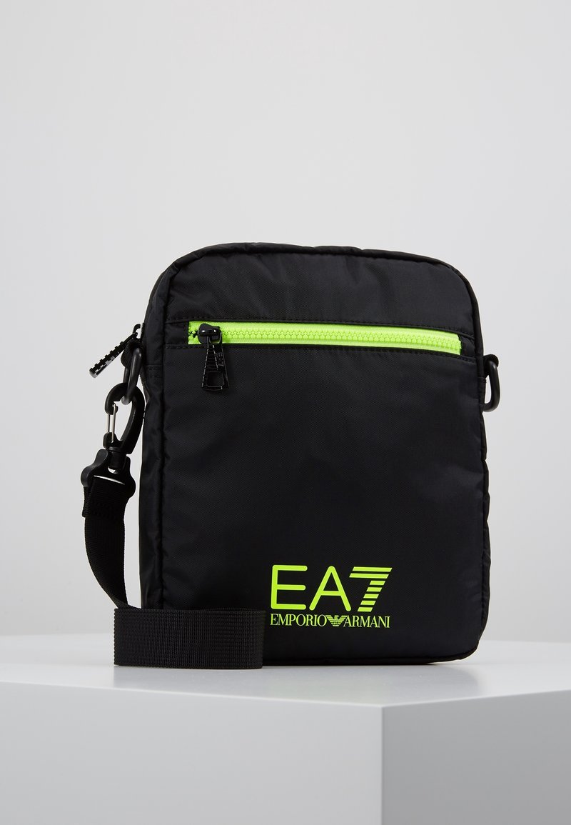 Czarna, prostokątna torba na ramię z neonowo zielonym zamkiem błyskawicznym i logo EA7 Emporio Armani, regulowany pasek mocowany na zatrzask.