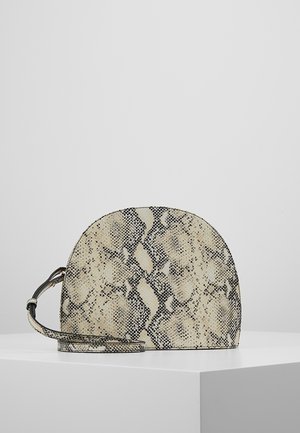 Kleine tas met halve maan vorm met beige en zwarte slangenhuidprint en bijpassende verstelbare schouderriem op witte ondergrond.