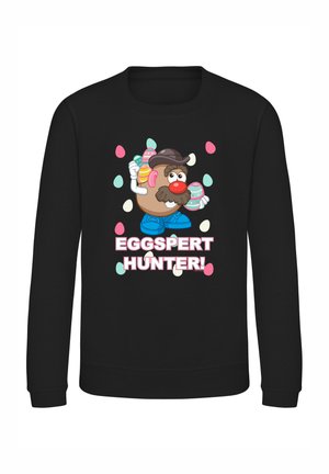Sort sweatshirt med en tegnet kartoffelkarakter, der har et overskæg og hat, holder dekorerede æg, med teksten "EGGSPERT HUNTER!" nedenfor.