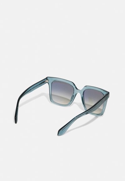 Ochelari de soare pătrați cu un cadru transparent de culoare albastru deschis, lentile de culoare gri închis și brațe accentuate cu nuanțe de teal. Prezintă un branding subtile pe tâmple.