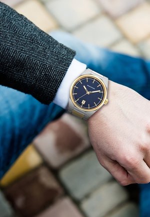 Armbanduhr aus Edelstahl mit einem strukturierten Zifferblatt in Marineblau, goldenen Akzenten, rechteckigen Markierungen und einer Datumsanzeige auf 3 Uhr.
