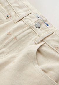 Jeans bej cu picioare largi din bumbac texturat, prevăzuți cu un nasture argintiu și o broderie subtilă în formă de inimă pe partea din față, evidențiind o tivă curată.