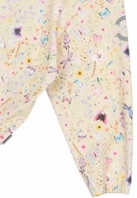 Tissu à motif floral aux couleurs pastel, avec des papillons et des fleurs. Matière légère avec poignets élastiqués et texture douce.