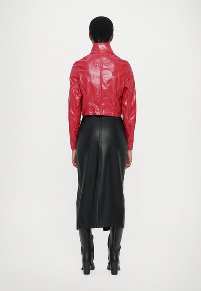 Jachetă croită din piele roșie, lucioasă, cu guler înalt, purtată cu o fustă lungă din piele neagră. Cizmele negre completează look-ul.