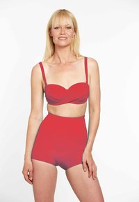 Sarkans bikini komplekts, kas sastāv no bandeau tipa augšda�ļas ar savītu dizainu un regulējamām siksnām, un augsto jostasvietu šortiem. Gluda tekstūra.