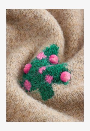 Tejido de lana color beige con un acabado texturizado, adornado con hojas de fieltro verdes y bayas de fieltro rosas dispuestas en un racimo.