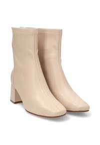 Botas de tobillo de cuero beige con punta cuadrada y tacón grueso, que cuentan con un diseño sin costuras y detalles de costura mínimos.