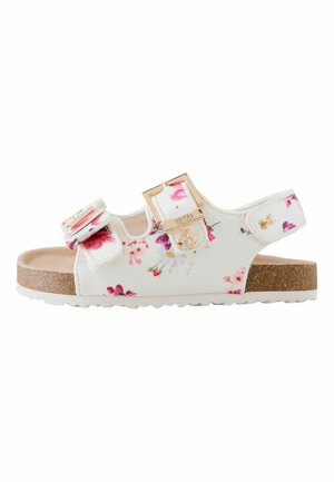 White floral children's sandal with cork sole, adjustable straps, gold buckle, and small charm detail.