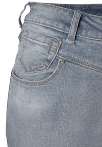 Svetlo modré denimové džínsy majú stredne vysoký pás, jedno zadné vrecko a kontrastné šitie pozdĺž švov.